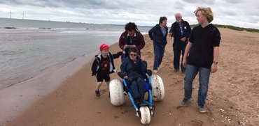 Family using the hippocampe beach wheelchair at Balmedie beach waterfront