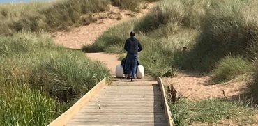 Parent pushing hippocampe chair along the boardwalk in the sand dunes